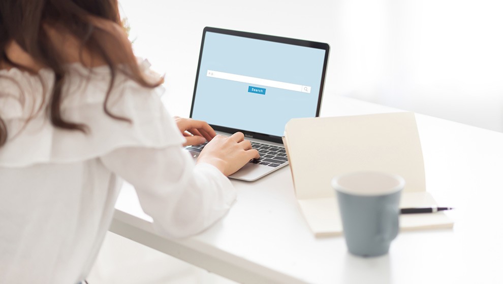 A woman types at her laptop, indicating her user search intent